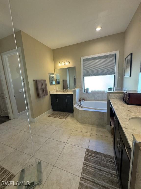 bathroom with tiled bath, tile patterned flooring, and vanity