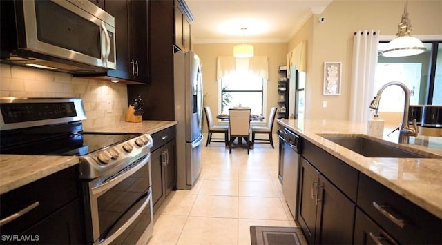 kitchen featuring light stone counters, hanging light fixtures, appliances with stainless steel finishes, light tile patterned flooring, and sink