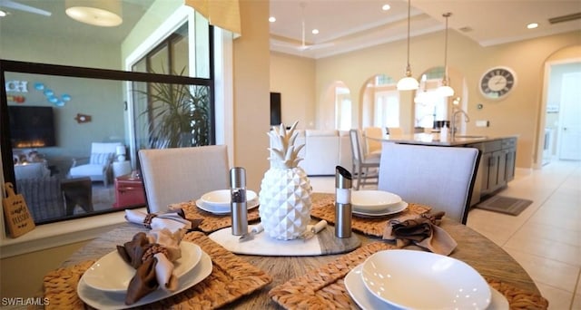 dining area with sink, a raised ceiling, and light tile patterned floors