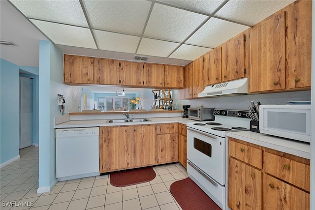 kitchen with sink, white appliances, a paneled ceiling, and light tile patterned flooring