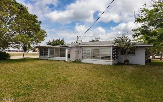 rear view of house featuring a yard and a sunroom