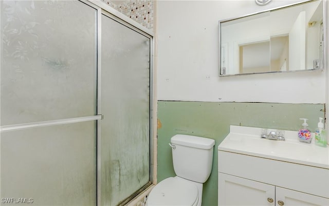 bathroom featuring toilet, an enclosed shower, and vanity