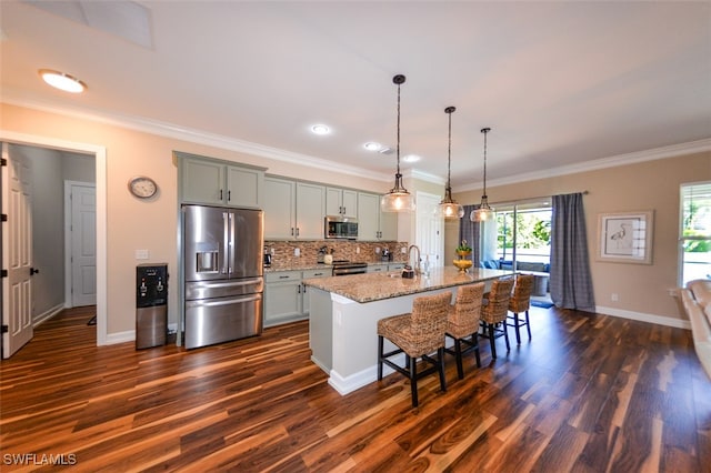 kitchen with gray cabinets, a breakfast bar, a kitchen island with sink, light stone counters, and stainless steel appliances