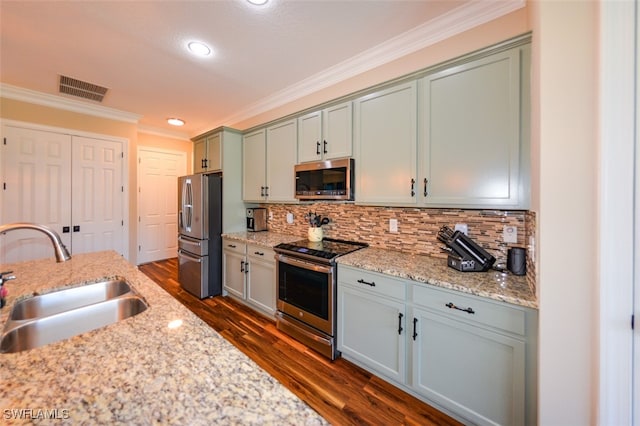 kitchen featuring appliances with stainless steel finishes, dark hardwood / wood-style floors, sink, backsplash, and light stone countertops