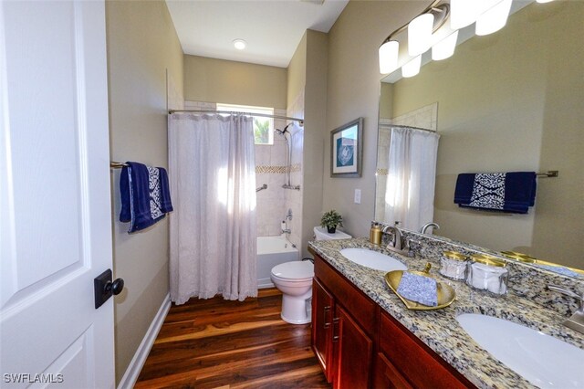 full bathroom with wood-type flooring, toilet, shower / bath combo with shower curtain, and vanity