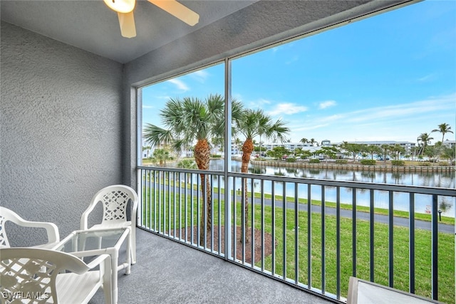 sunroom with ceiling fan and a water view