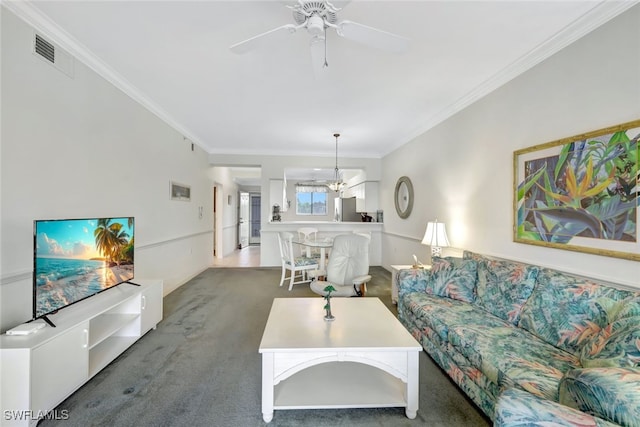 living room with ornamental molding, ceiling fan with notable chandelier, and dark carpet