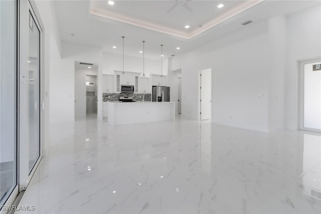 unfurnished living room with a raised ceiling and ceiling fan