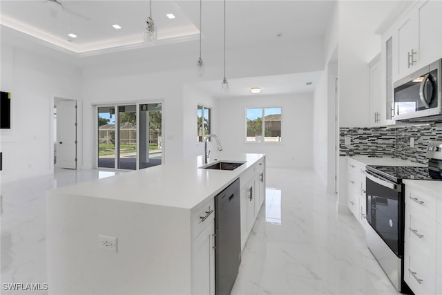 kitchen with sink, an island with sink, decorative light fixtures, white cabinetry, and stainless steel appliances