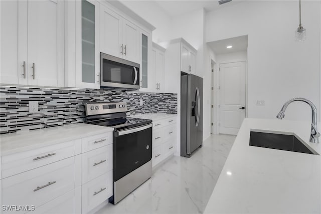 kitchen featuring white cabinets, hanging light fixtures, sink, light stone countertops, and appliances with stainless steel finishes