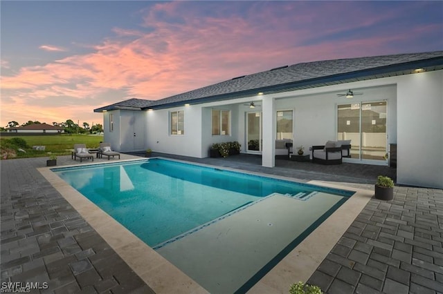 pool at dusk featuring ceiling fan, an outdoor hangout area, and a patio