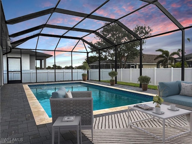 pool at dusk featuring a lanai and a patio