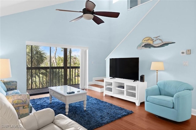 living room featuring a high ceiling, ceiling fan, and dark wood-type flooring