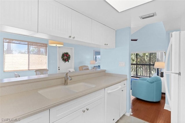 kitchen with white appliances, white cabinetry, light wood-type flooring, and sink