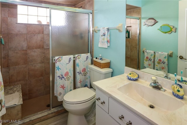 bathroom featuring toilet, vanity, and a shower with shower door