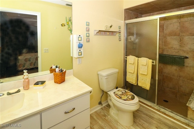 bathroom featuring toilet, vanity, hardwood / wood-style floors, and a shower with shower door