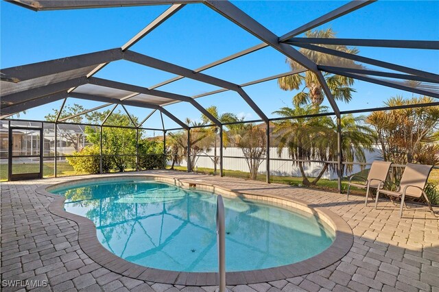 view of swimming pool featuring glass enclosure and a patio area