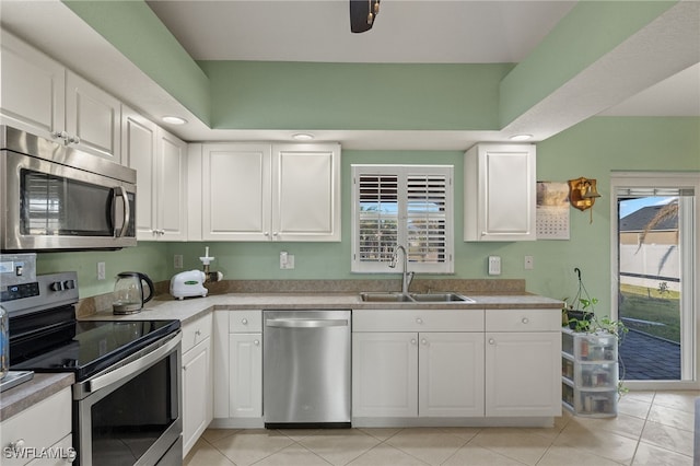 kitchen featuring light tile patterned floors, stainless steel appliances, white cabinetry, and sink