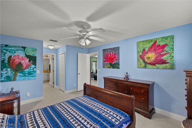 bedroom featuring connected bathroom, ceiling fan, a closet, and light tile patterned floors