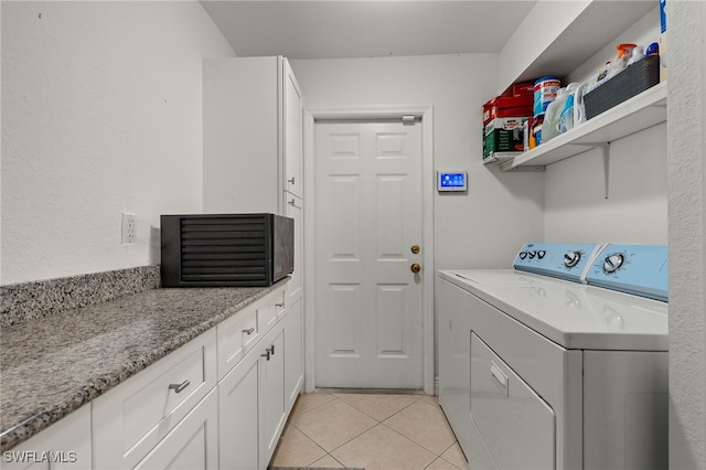 laundry area with washing machine and clothes dryer, light tile patterned floors, and cabinets