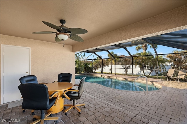 view of swimming pool with a patio, glass enclosure, and ceiling fan