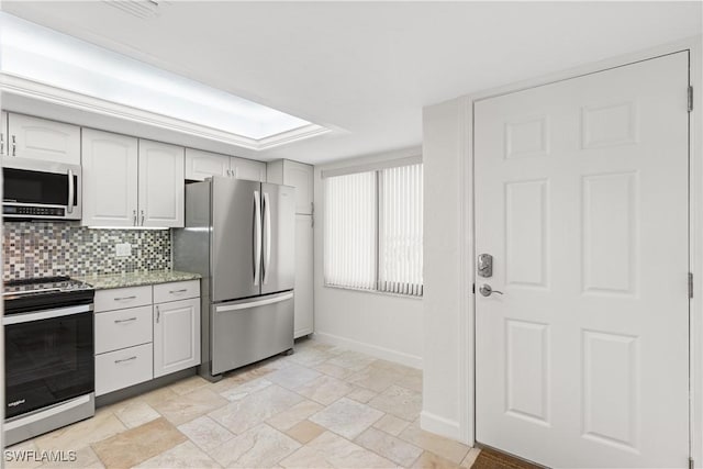 kitchen featuring white cabinets, decorative backsplash, a skylight, light stone countertops, and appliances with stainless steel finishes