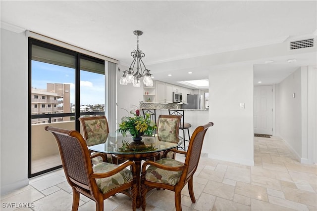 dining room featuring an inviting chandelier, crown molding, and expansive windows