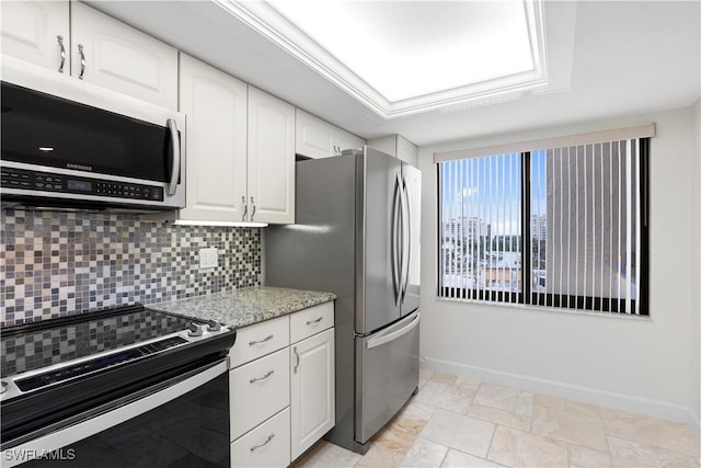 kitchen with light stone counters, stainless steel appliances, white cabinets, and tasteful backsplash