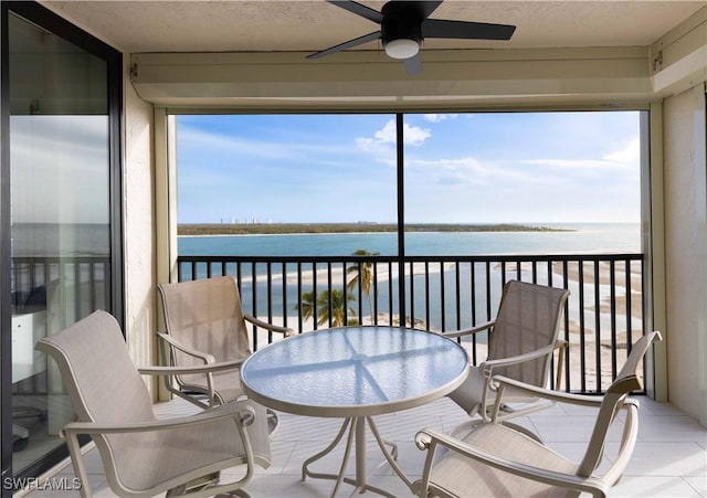 sunroom / solarium featuring ceiling fan and a water view