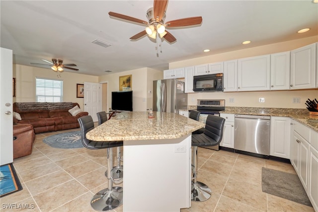 kitchen with a kitchen bar, a center island, white cabinets, and stainless steel appliances