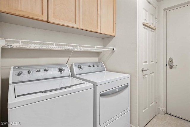 laundry room featuring washer and clothes dryer, cabinets, and light tile patterned flooring