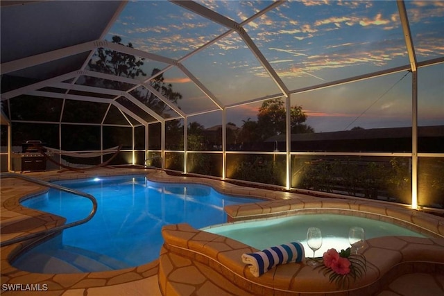 pool at dusk featuring glass enclosure and a patio area