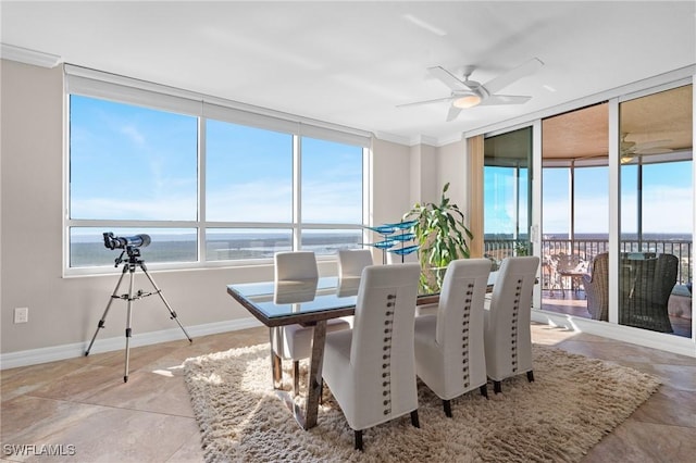 sunroom with ceiling fan and a water view