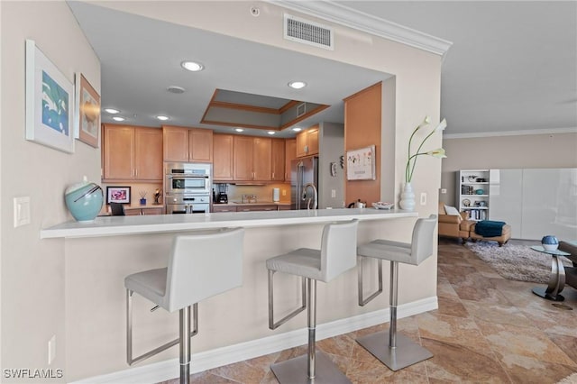 kitchen with ornamental molding, kitchen peninsula, appliances with stainless steel finishes, and a breakfast bar area