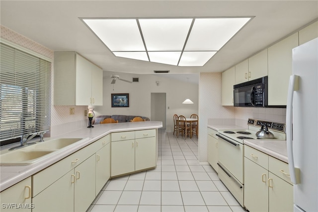 kitchen featuring sink, decorative backsplash, white appliances, and kitchen peninsula