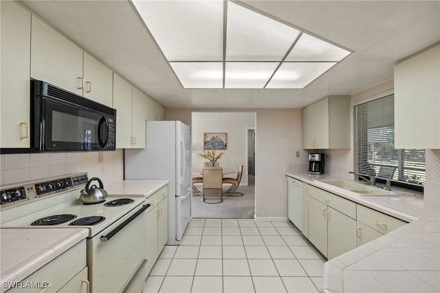 kitchen featuring sink, white appliances, decorative backsplash, tile countertops, and cream cabinetry