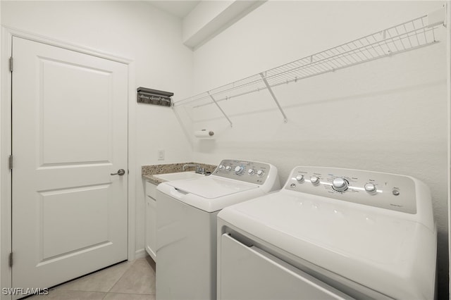 washroom with sink, cabinets, washing machine and dryer, and light tile patterned floors