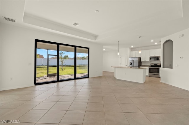 unfurnished living room featuring a tray ceiling and light tile patterned floors