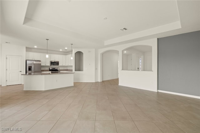 interior space featuring appliances with stainless steel finishes, white cabinetry, decorative light fixtures, and light tile patterned floors