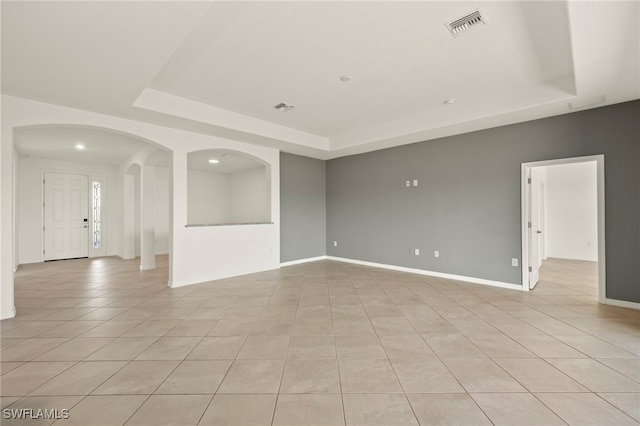 tiled spare room with a raised ceiling