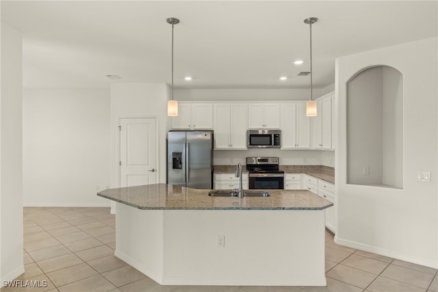 kitchen featuring dark stone countertops, stainless steel appliances, light tile patterned floors, sink, and white cabinetry