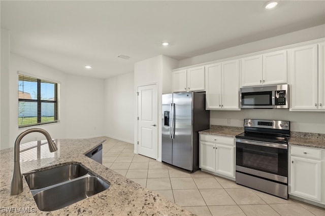 kitchen with stainless steel appliances, light stone countertops, white cabinets, and sink