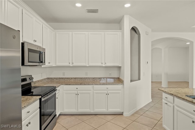 kitchen with white cabinets, stainless steel appliances, light stone counters, and light tile patterned flooring