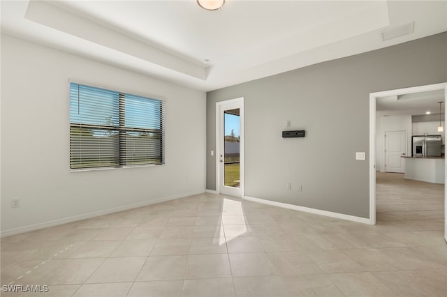 spare room with light tile patterned flooring and a tray ceiling