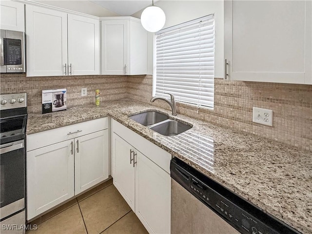 kitchen featuring appliances with stainless steel finishes, decorative light fixtures, white cabinetry, sink, and light tile patterned floors