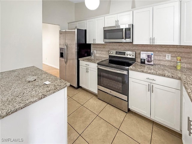 kitchen featuring light stone countertops, white cabinetry, appliances with stainless steel finishes, and light tile patterned flooring