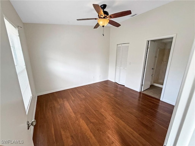 unfurnished bedroom featuring ceiling fan, dark wood-type flooring, and ensuite bath