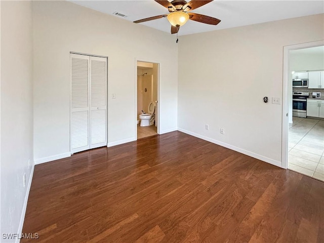 unfurnished bedroom with hardwood / wood-style floors, a closet, ensuite bath, and ceiling fan