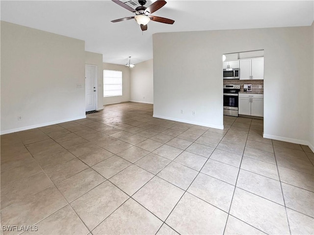 unfurnished living room featuring ceiling fan with notable chandelier, light tile patterned flooring, and vaulted ceiling