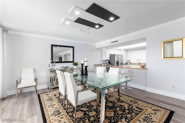 dining space with crown molding and light hardwood / wood-style flooring